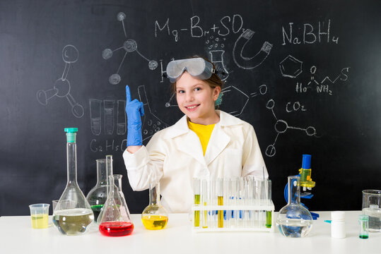schoolgirl in chemistry lab pointing at formula on blackboard