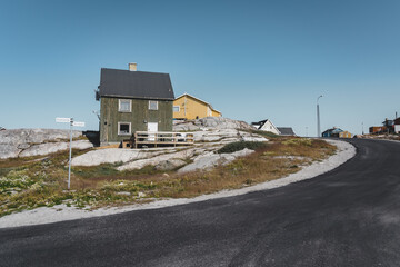 Typical wooden colourful fisher house with iceberg in Disko bay area Greenland and Ilulissat. Typical architecture in the arctic circle. Summer and blue sky.