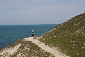 View of the blue sea from the mountainside. A young man looks at the sea. 