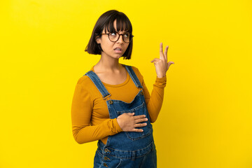 Young pregnant woman over isolated yellow background with problems making suicide gesture