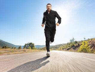 Man in black tracksuits running outdoors on an asphalt road