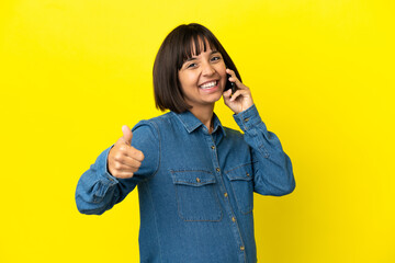 Pregnant woman using mobile phone isolated on yellow background with thumbs up because something good has happened