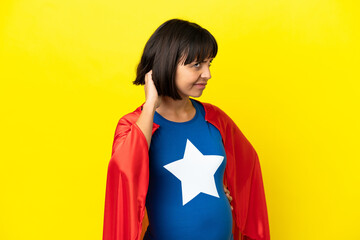 Super Hero pregnant woman isolated on yellow background having doubts