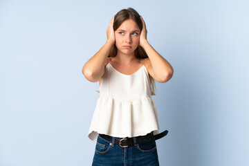 Young Lithuanian woman isolated on blue background frustrated and covering ears