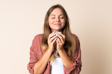 Young Lithuanian woman isolated on beige background holding a donut