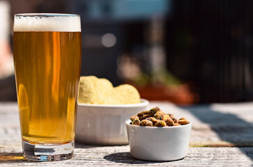 Glass of beer and pistachio nuts on patio table