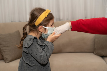 Little girl in medical protective mask kiss her parent's hand in a rubber glove. Muslim tradition in Eid Mubarak. Child show respect for mother or grandmother during Ramadan (aka: Ramazan bayrami).