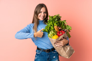 Young Lithuanian woman holding a grocery shopping bag giving a thumbs up gesture
