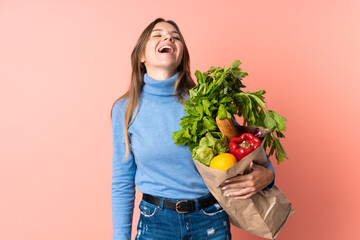 Young Lithuanian woman holding a grocery shopping bag laughing