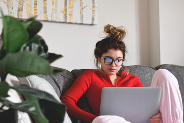 Young teenage girl sitting on a couch using laptop computer