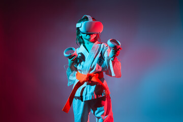 Young caucasian girl in karate uniform playing video games with virtual reality