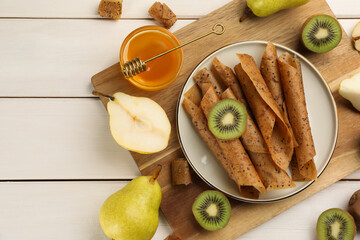 Flat lay composition with delicious fruit leather rolls on white wooden table