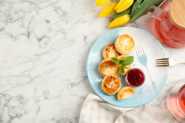 Delicious cottage cheese pancakes with jam and icing sugar on white marble table, flat lay. Space for text