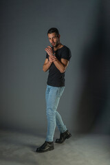 Fototapeta premium Studio photoshoot of a good-looking man posing in jeans and black shirt