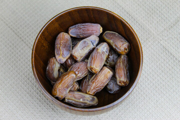 Wooden bowl with dates on the table. Fruit on a wooden tray. Fruit dates. Walnut kernels. The concept of Ramadan.