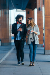 Fototapeta premium Business couple ( colleagues ) walking along the futuristic modern station (airport) while drinking coffee and talking to each other.