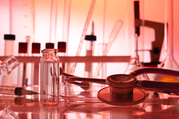 Chemical table with lab glassware and stethoscope in red colors. Test tubes, liquid flasks, medical gadgets in chemical laboratory. Biotech research laboratory with biochemicals on the lab desk.