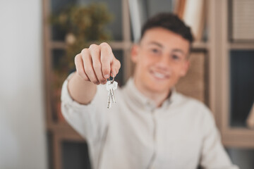 Focus on bunch of keys from house flat apartment in hand of smiling teenager. Blurred portrait of...