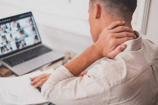 Close Up Rear View Stressed Young Man Touching Lower Neck Feeling Discomfort, Suffering From Sudden Pain Due To Sedentary Lifestyle Or Long Computer Overwork In Incorrect Posture At Home Office..