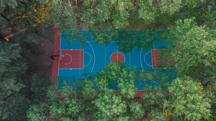 Aerial view of basketball court hidden by trees in a park. field proper markings and proportions according standards.