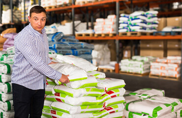 Cheerful man buying compost soil for gardening in hypermarket
