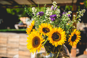 Flower arrangement with sunflowers and other kind of flowers in glass jar in a outdoor wedding in the day