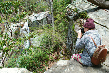 A photographer taking a photo sitting on a rock