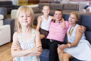 Happy girl is standing near new sofa in furniture store