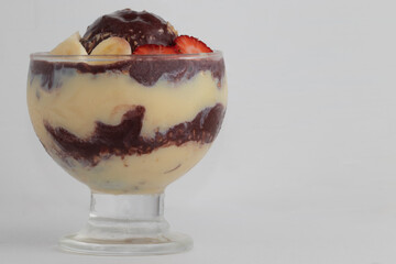 Delicious Brazilian açaí with granola, strawberry, banana and condensed and canned milk on white background..
