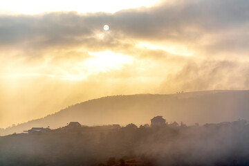 Dawn on plateau in morning with colorful sky, while sun rising from horizon shines down to small village covered with fog shrouded  landscape so beautiful idyllic countryside Dalat plateau, Vietnam