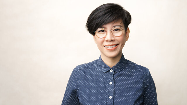 Beautiful studio portrait of a smart look asian middle aged woman with round eye glasses in casual, she looking to camera and smile with satisfied. Progressive lens, Eyewear, 40s, Short hairstyle.