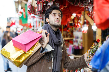 Fototapeta na wymiar Smiling man choosing decorations at Christmas market outdoor