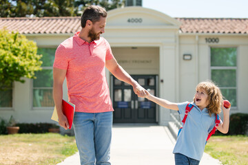 Obraz premium Father walking son to school. Parent and happy pupil of primary school schoolboy with backpack.