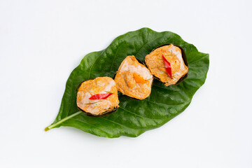 Thai streamed fish curry in banana leaves on noni or morinda citrifolia leaves on white background.