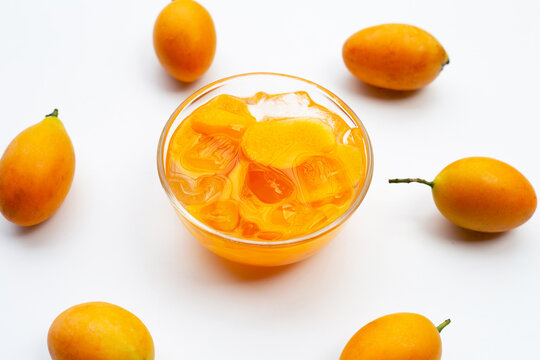 Marian plum fruits in syrup with ice in glass bowl on white