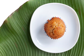 Top view of sweet banana muffins in white plate on banana leaf isolated on white background.