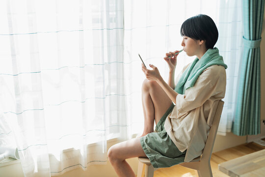 歯を磨きながら携帯電話を見る女性