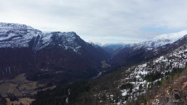 Reverse aerial revealing spectacular viewpoint and family in mountain winter roads - landscape Norway Nesheim Teigdalen Voss Vestland