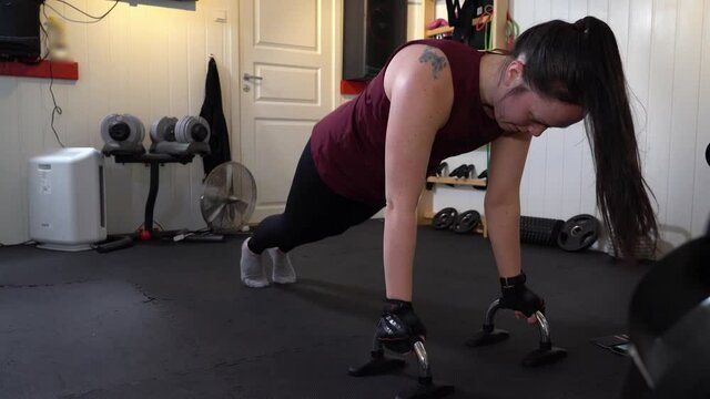 Female performing One-Legged Push-Up stand - Alone workout in basement