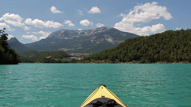 Beautiful sunny day for kayaking at emerald lake. Wonderlust view of highland lake with forest and mountain under the sunlight and sky with clouds. Catalonia, Spain