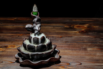 Ceramic backflow incense burner in the form of lotus flower. Incense cones holder. Dark mystic concept. - obrazy, fototapety, plakaty