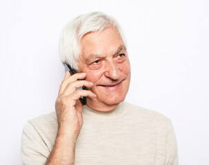 senior man in casual outfit using modern smartphone and laughing out loud while standing on white background.