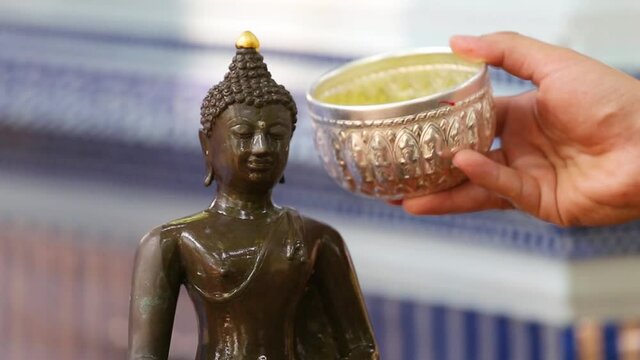 Close up Face of Buddha statue with Hand of sprinkle water onto a Buddha image.
Songkran the most famous festival of Thailand