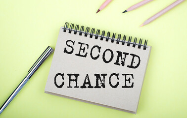 SECOND CHANCE text on the notebook with pen on yellow background