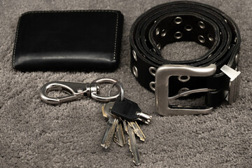 wallet, keys and leather belt on black background, men accessories concept