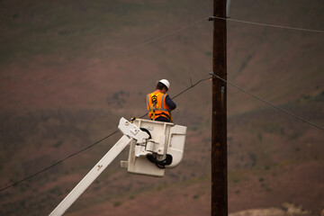 lineman technician working on fixing power lines in rural area of Naches Washington Yakima County for power company