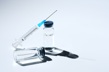 Close up glass vial with flu vaccine and syringe with needle. The concept of vaccination or...