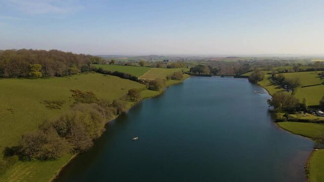 4K flying over hawkridge reservoir, drone raising over the water revealing the fishing boats docks and the water dam wall, 60fps.