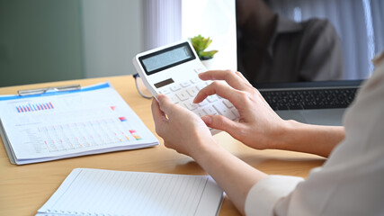 Close up view of female accountant using calculator for calculating finance at office desk.