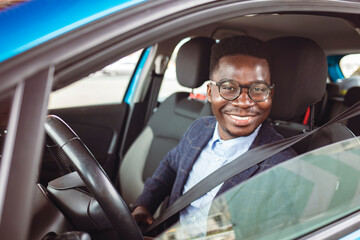 Businessman in his car fastening the seatbelt, safe driving concept. Car safety. Business man fastening seat belt in auto, driving to work, copy space. Man wearing seat belt in car before driving